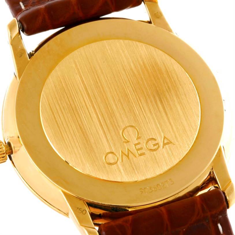 The image shows the back case of an Omega De Ville Men's Yellow Gold Silver Dial Men's Yellow Gold Silver Dial watch, highlighting its golden finish and leather strap.