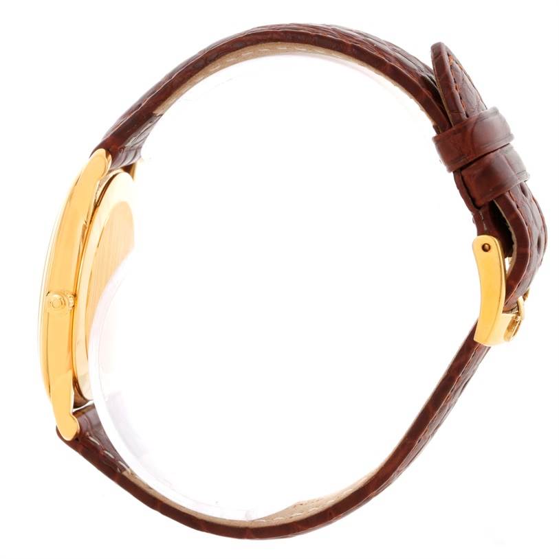 This side view of the Omega De Ville Men's Yellow Gold Silver Dial Men's Yellow Gold Silver Dial watch shows the brown leather strap, gold case, and buckle.