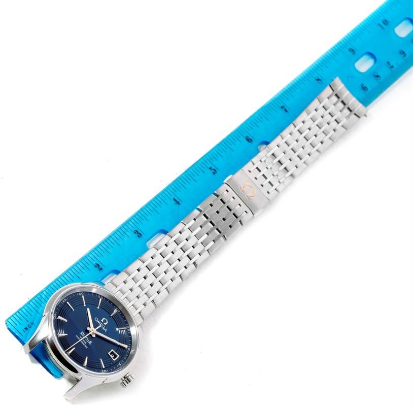 This image shows the Omega De Ville 431.33.41.21.03.001 Men's Stainless Steel Blue Dial 431.33.41.21.03.001 Men's Stainless Steel Blue Dial watch laying flat next to a blue ruler, highlighting the face and metal bracelet.