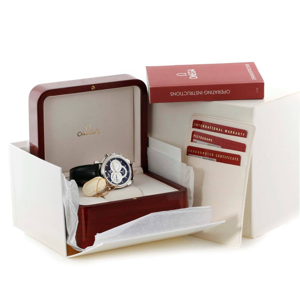 The image shows an Omega De Ville 4847.50.31 Men's Stainless Steel Black Dial 4847.50.31 Men's Stainless Steel Black Dial watch at an angle inside an open box, along with warranty cards and an instruction manual.