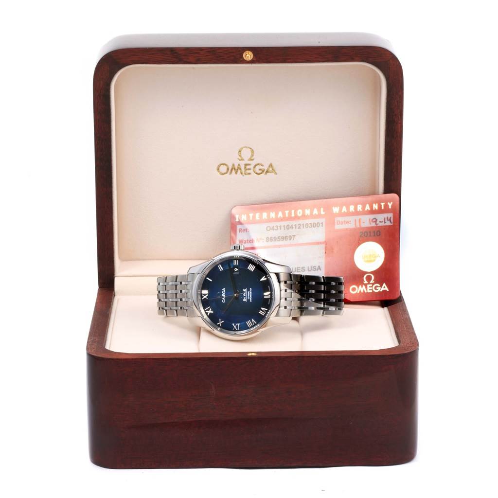 The Omega De Ville 431.10.41.21.03.001 Men's Stainless Steel Blue Dial 431.10.41.21.03.001 Men's Stainless Steel Blue Dial watch is shown from the front, nestled in an open wooden box with an International Warranty card beside it.