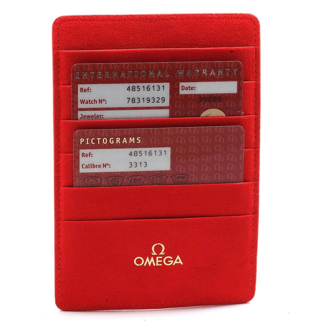 The image shows the warranty and pictogram cards for the Omega De Ville 4851.61.31 Men's Stainless Steel Red Dial 4851.61.31 Men's Stainless Steel Red Dial watch, placed in a red Omega cardholder.