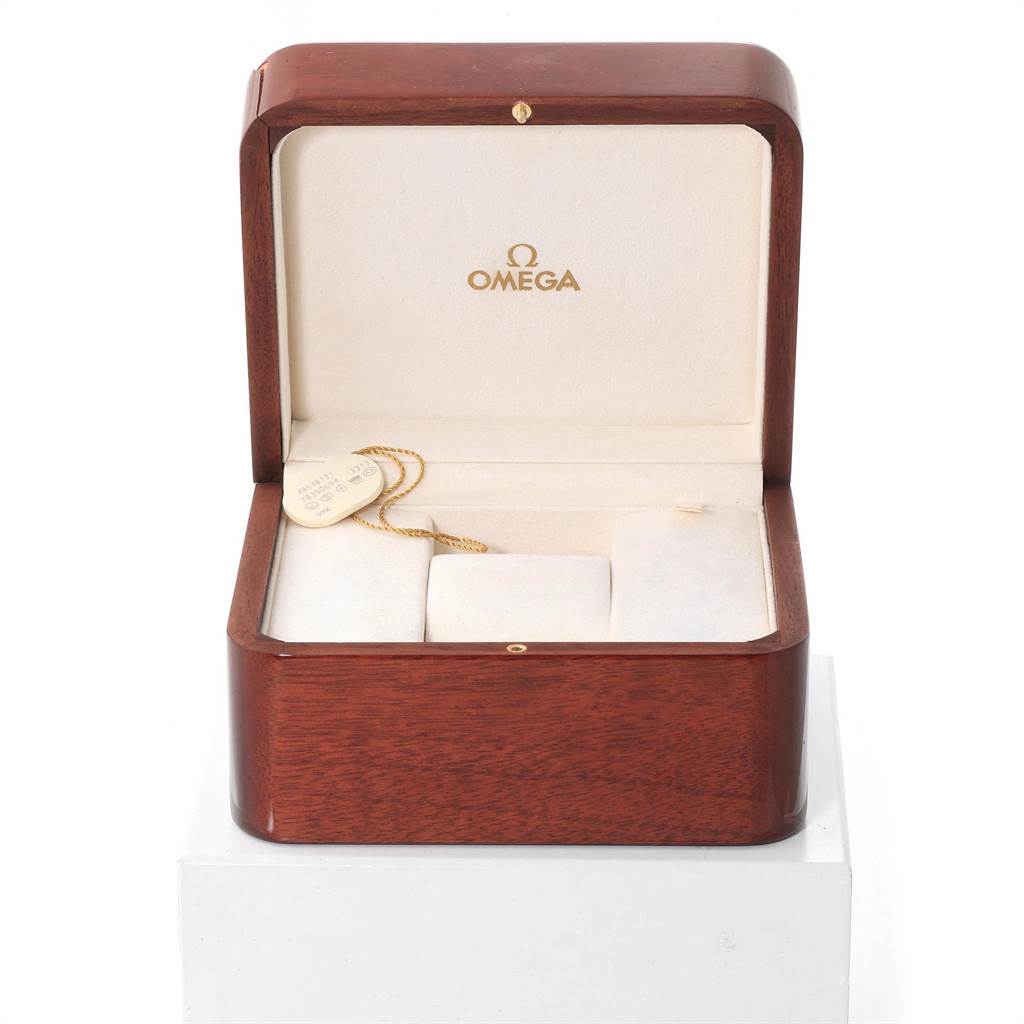 The image shows an open wooden Omega De Ville 4851.61.31 Men's Stainless Steel Red Dial 4851.61.31 Men's Stainless Steel Red Dial watch box with its interior displayed, including a tag.