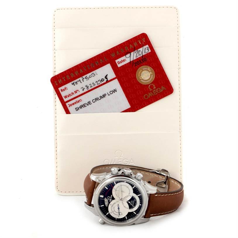 The image shows an Omega De Ville 4847.50.31 Men's Stainless Steel Black Dial 4847.50.31 Men's Stainless Steel Black Dial watch with a brown leather strap, placed in front of its international warranty card and case.