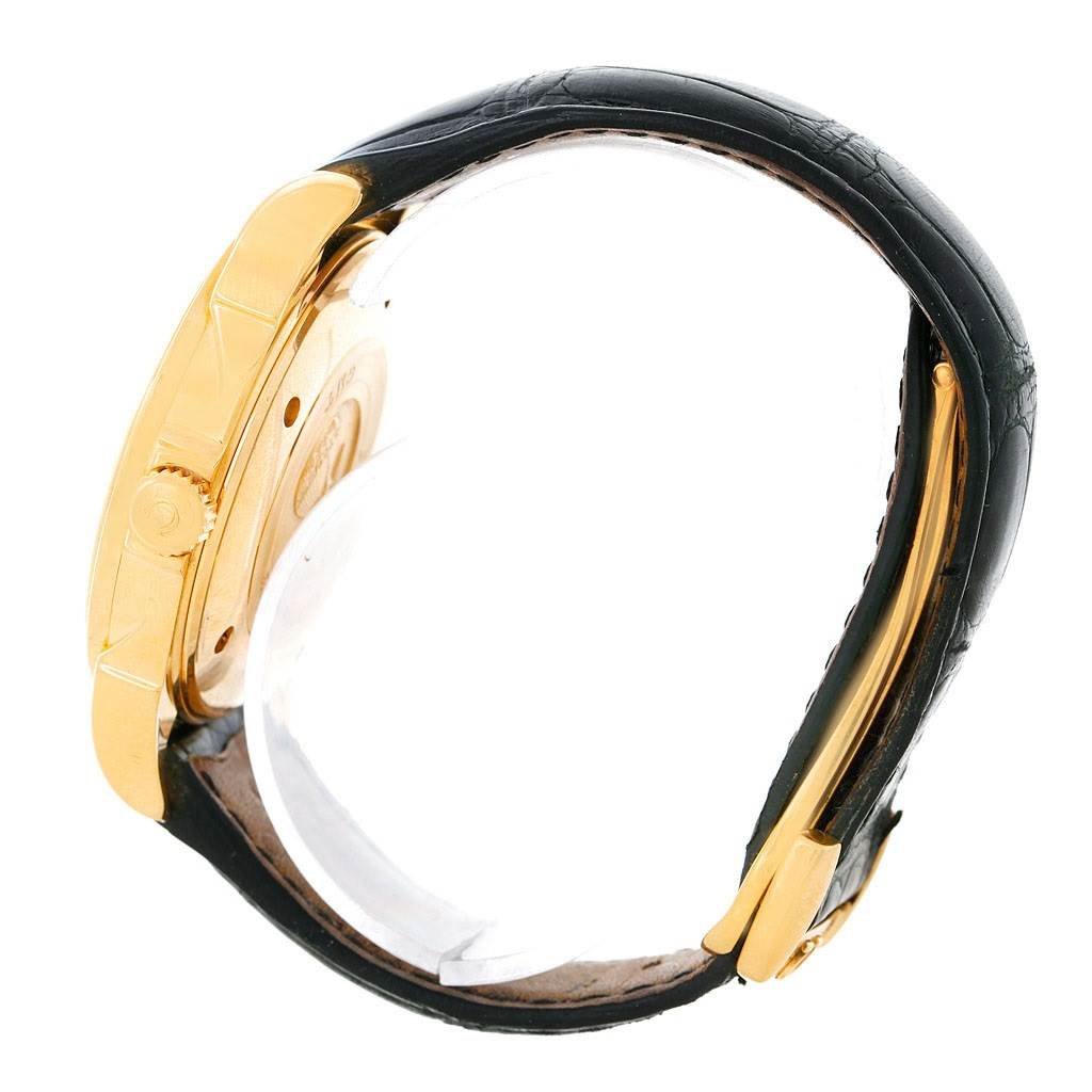 The image shows a side view of an Omega De Ville 4633.30.31 Men's Yellow Gold Silver Dial 4633.30.31 Men's Yellow Gold Silver Dial watch, highlighting the gold bezel, crown, and black leather strap.