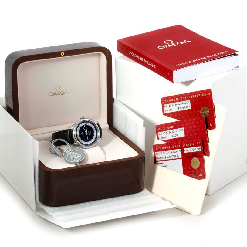The Omega De Ville 431.33.41.21.01.001 Men's Stainless Steel Black Dial 431.33.41.21.01.001 Men's Stainless Steel Black Dial watch is shown in its open case at an angle, accompanied by documentation and a red instruction manual.