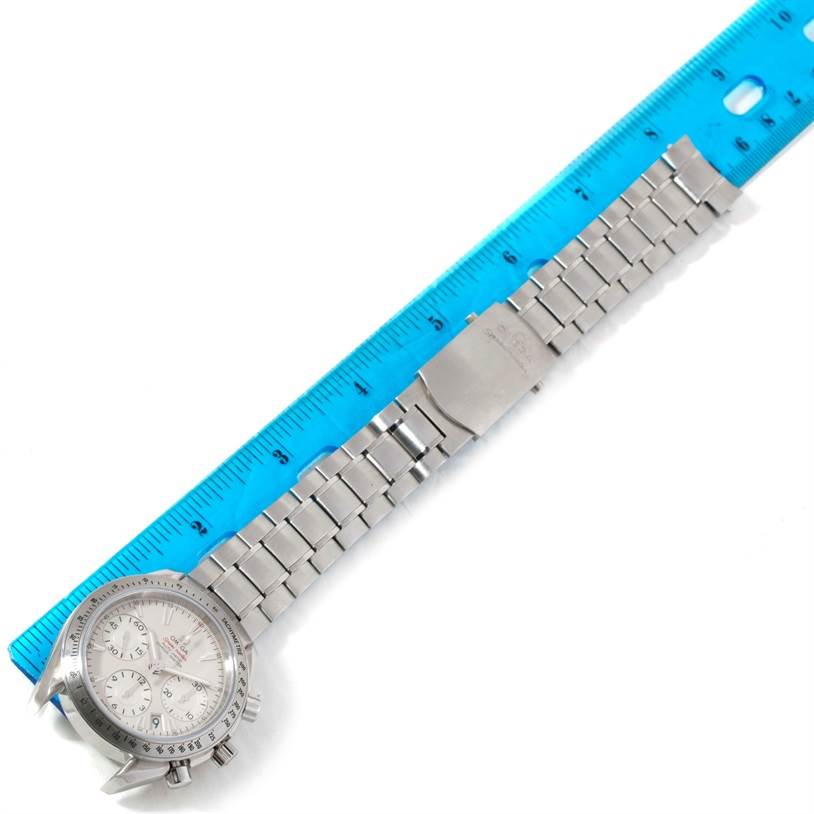 The Omega Speedmaster 323.10.40.40.02.001 Men
s Stainless Steel Silver Dial 323.10.40.40.02.001 Men
s Stainless Steel Silver Dial watch is shown from a top-down angle, highlighting the face, bracelet, and clasp next to a blue ruler.