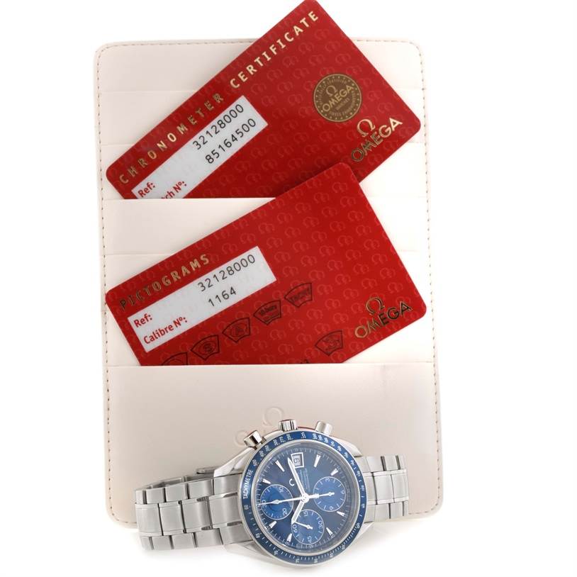 The image shows an Omega Speedmaster 3212.80.00 Men
s Stainless Steel Blue Dial 3212.80.00 Men
s Stainless Steel Blue Dial watch with a blue dial, on a bracelet, and its accompanying chronometer certificate and pictogram cards.