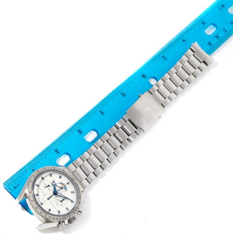 The image shows an Omega Speedmaster 3575.20.00 Men
s Stainless Steel White Dial 3575.20.00 Men
s Stainless Steel White Dial watch laid flat, with a blue ruler indicating its length.