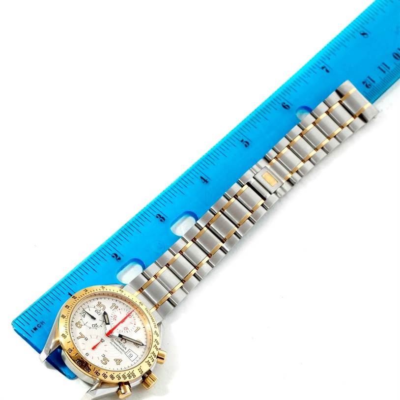 The Omega Speedmaster 3313.33.00 Men's Steel and Gold (two tone) White Dial 3313.33.00 Men's Steel and Gold (two tone) White Dial watch is shown at an angled top-down view with its bracelet measured against a blue ruler.