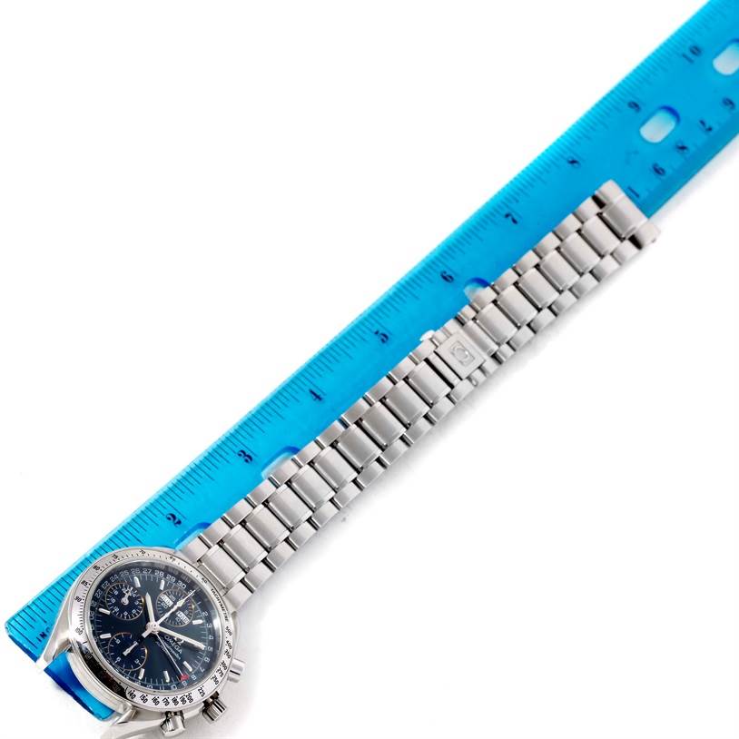 The image shows an Omega Speedmaster 3523.80.00 Men
s Stainless Steel Blue Dial 3523.80.00 Men
s Stainless Steel Blue Dial watch lying flat, with a focus on its bracelet measured against a blue ruler.