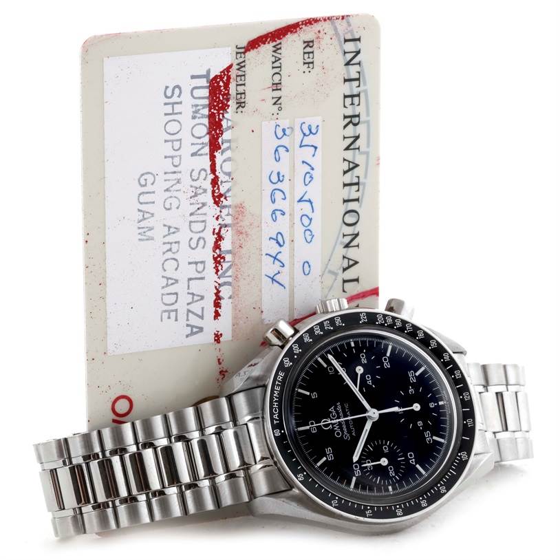 The image shows an Omega Speedmaster 3510.50.00 Men
s Stainless Steel Black Dial 3510.50.00 Men
s Stainless Steel Black Dial watch placed in front of its international warranty card at an angled view.