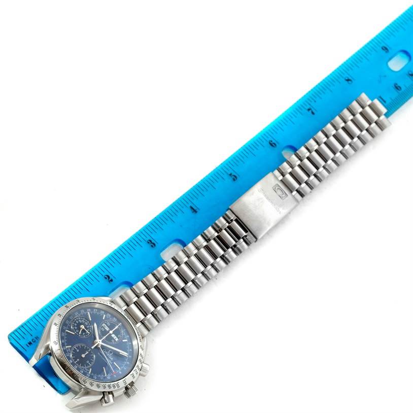 The image shows an Omega Speedmaster 3523.80.00 Men
s Stainless Steel Blue Dial 3523.80.00 Men
s Stainless Steel Blue Dial watch with a metal bracelet, laid flat next to a blue ruler, in a top-down angle.