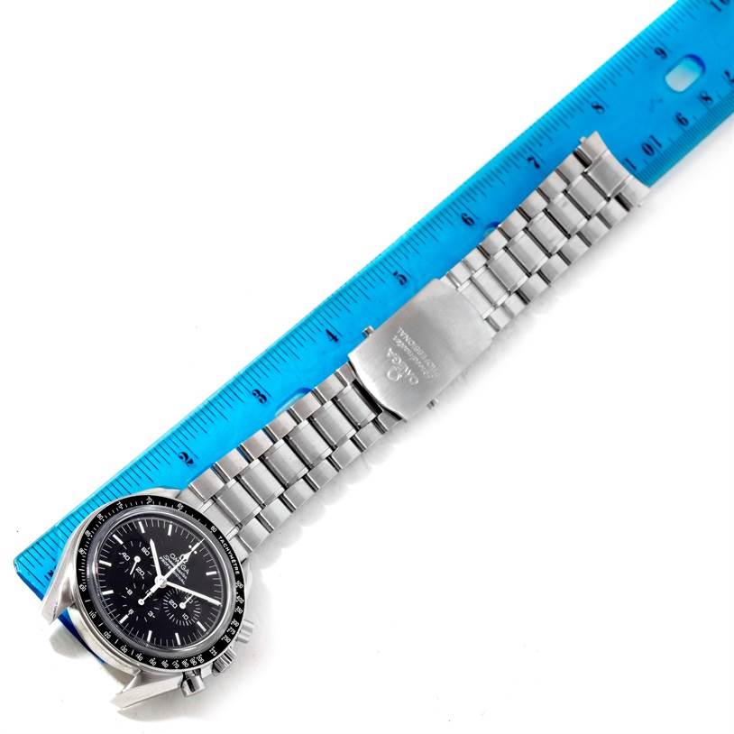 The image shows an overhead view of an Omega Speedmaster 3573.50.00 Men
s Stainless Steel Black Dial 3573.50.00 Men
s Stainless Steel Black Dial watch, displaying its face, stainless steel bracelet, and clasp alongside a ruler.