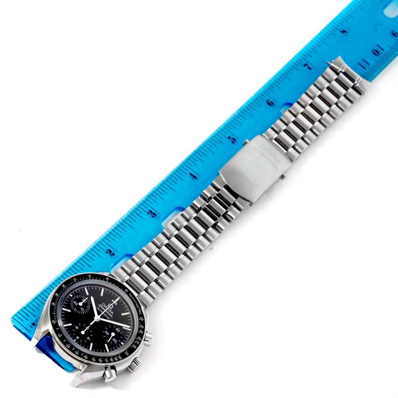 The Omega Speedmaster 3539.50.00 Men
s Stainless Steel Black Dial 3539.50.00 Men
s Stainless Steel Black Dial watch is shown from an aerial view, featuring the watch face and metal bracelet placed alongside a ruler.