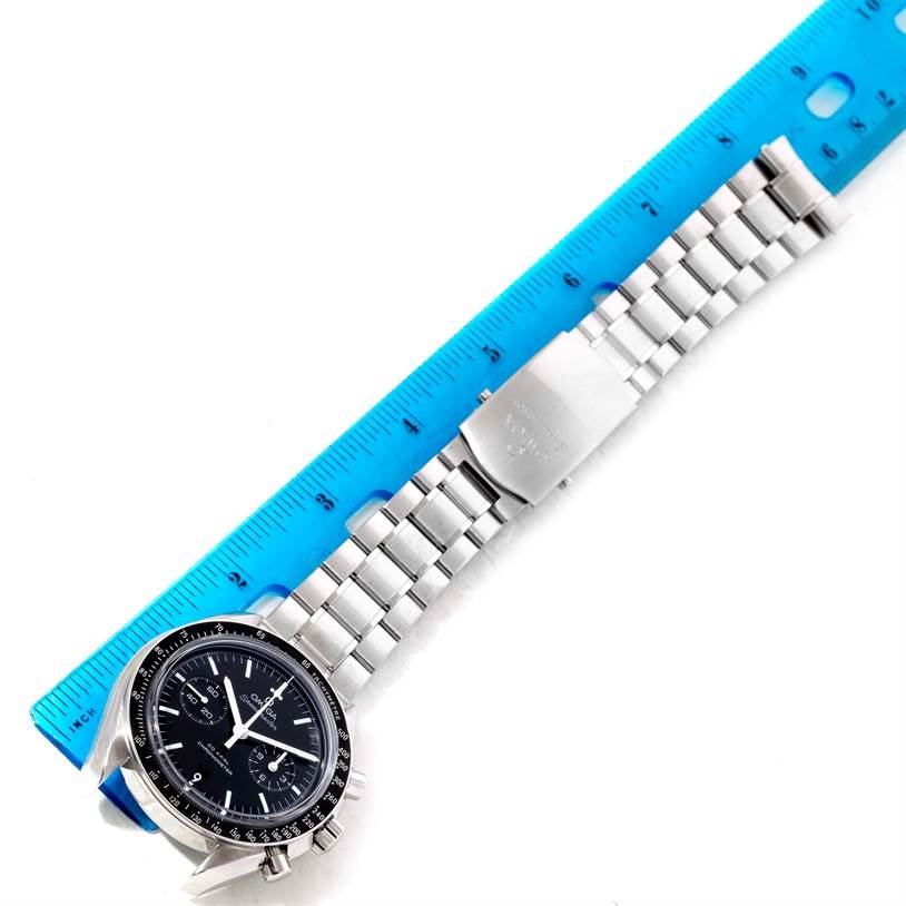 The Omega Speedmaster 311.30.44.51.01.002 Stainless Steel Black Dial 311.30.44.51.01.002 Stainless Steel Black Dial watch is shown lying flat, featuring its face, bezel, and metal bracelet alongside a blue ruler.