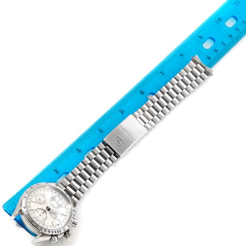 The image shows an Omega Speedmaster 3521.30.00 Men
s Stainless Steel Silver Dial 3521.30.00 Men
s Stainless Steel Silver Dial watch laid flat next to a ruler, highlighting the strap and clasp.