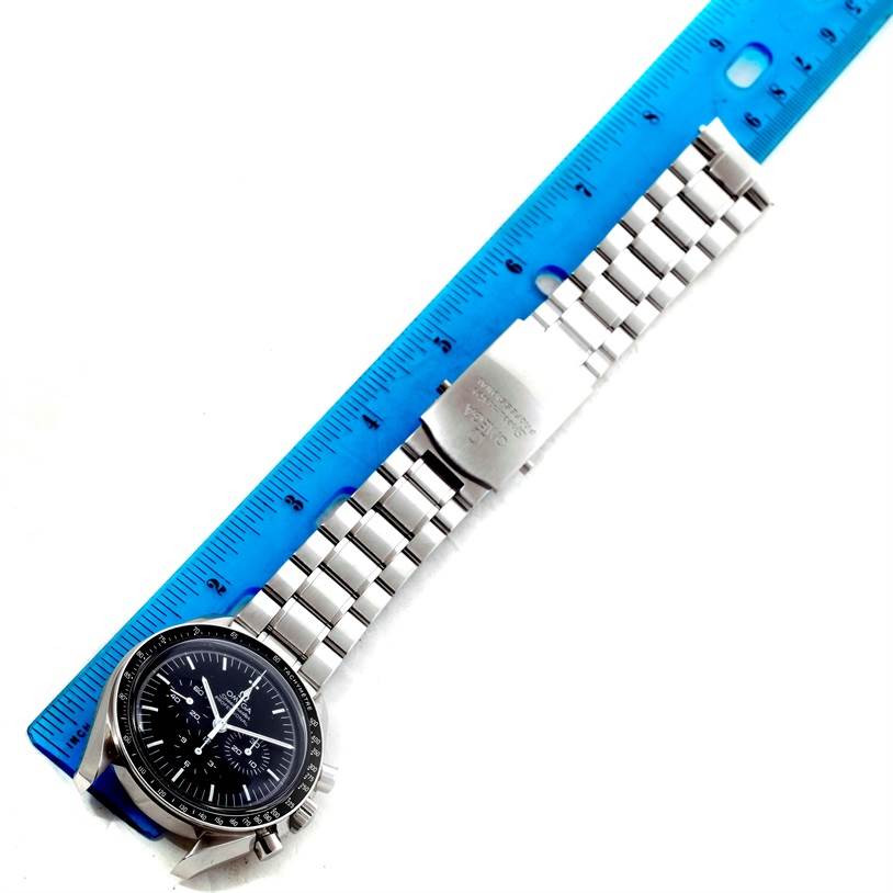 The Omega Speedmaster 311.30.42.30.01.005 Men
s Stainless Steel Black Dial 311.30.42.30.01.005 Men
s Stainless Steel Black Dial watch is displayed flat, showing the face, bezel, and metal bracelet next to a blue ruler for scale.