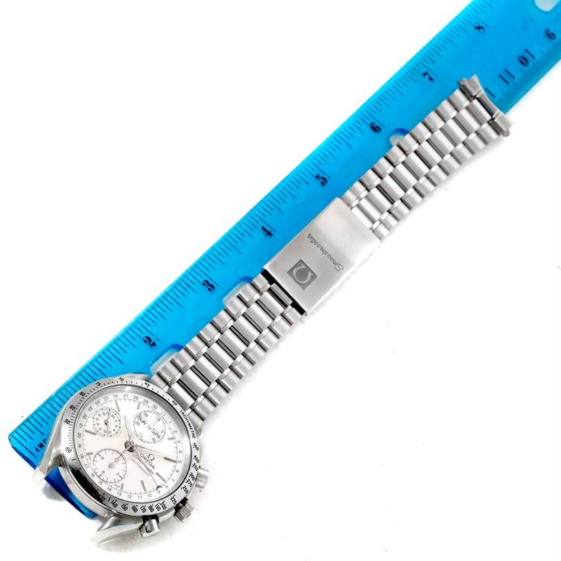 The image shows an Omega Speedmaster 3521.30.00 Men
s Stainless Steel Silver Dial 3521.30.00 Men
s Stainless Steel Silver Dial watch laid flat, alongside a blue ruler to measure its metal bracelet.