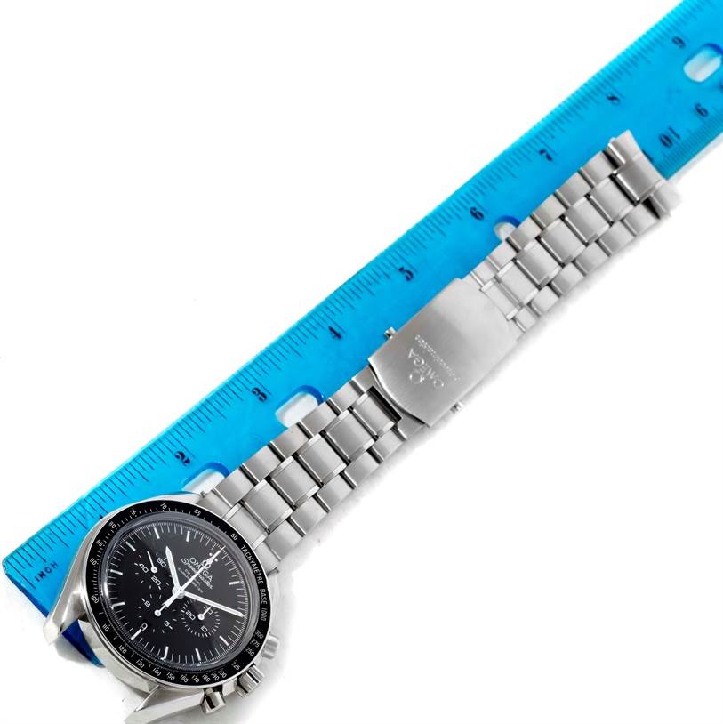 The Omega Speedmaster 311.30.44.50.01.002 Men
s Stainless Steel Black Dial 311.30.44.50.01.002 Men
s Stainless Steel Black Dial watch is shown at an angle, featuring its face, case, and metal bracelet against a blue ruler.