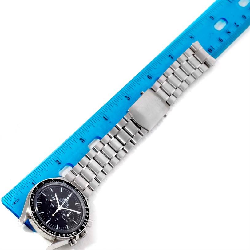 The Omega Speedmaster 3573.50.00 Men
s Stainless Steel Black Dial 3573.50.00 Men
s Stainless Steel Black Dial watch is shown from a top-down angle alongside a blue ruler.