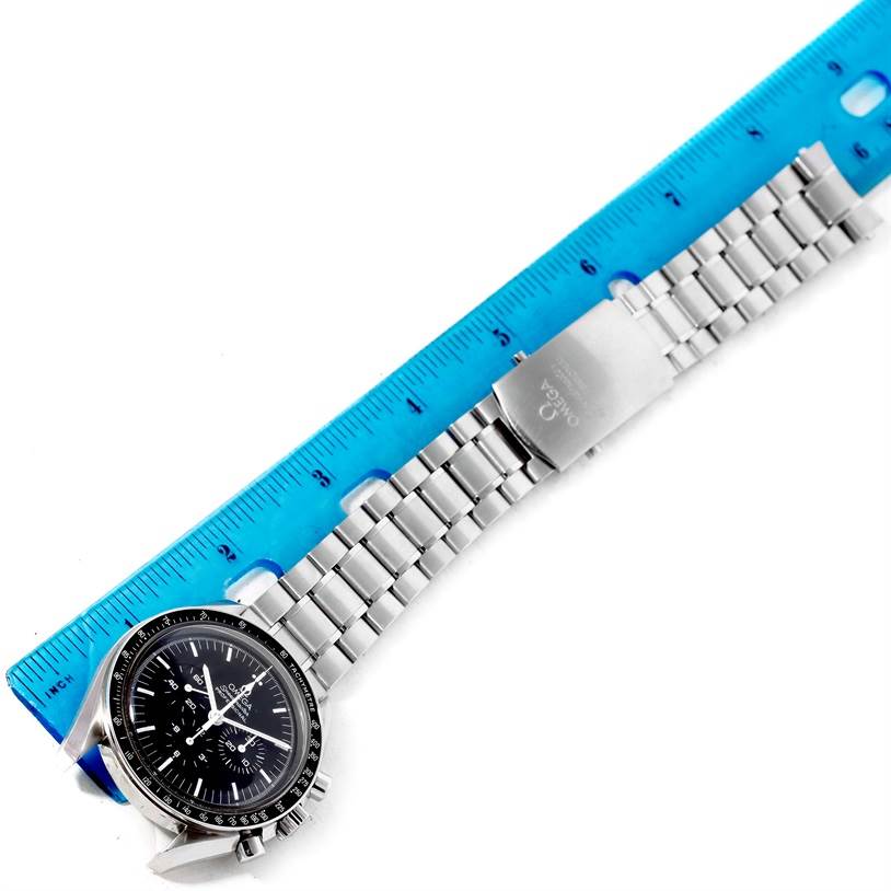 The image shows an Omega Speedmaster 3570.50.00 Men
s Stainless Steel Black Dial 3570.50.00 Men
s Stainless Steel Black Dial watch laying flat, with its face, bezel, and metal bracelet visible, next to a blue ruler for scale.