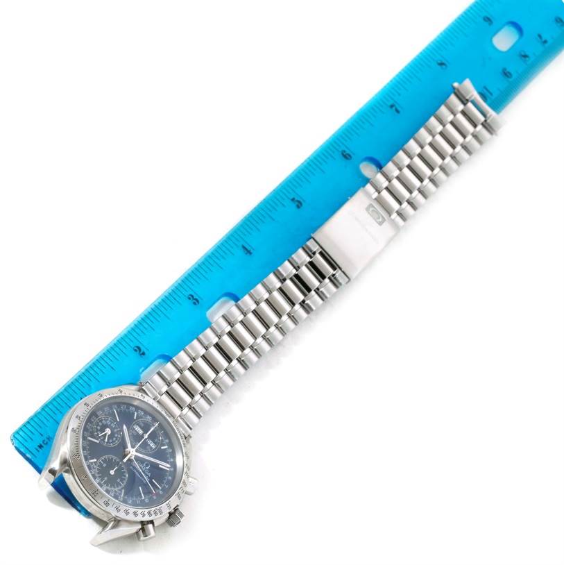 This Omega Speedmaster 3523.80.00 Men
s Stainless Steel Blue Dial 3523.80.00 Men
s Stainless Steel Blue Dial watch is shown at an angle along a blue ruler, highlighting the watch face and metal bracelet.