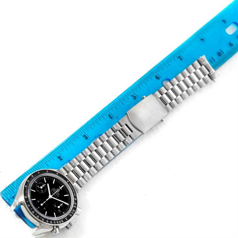 The image shows a top-down view of an Omega Speedmaster 3539.50.00 Men
s Stainless Steel Black Dial 3539.50.00 Men
s Stainless Steel Black Dial watch with its stainless steel bracelet beside a blue ruler.