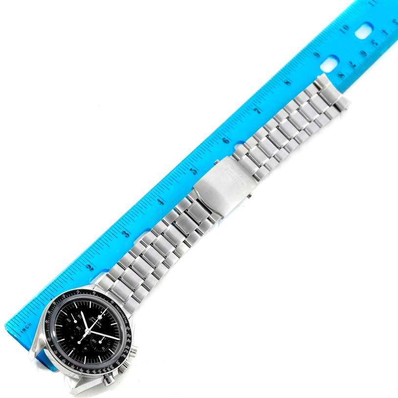 The Omega Speedmaster 3573.50.00 Men
s Stainless Steel Black Dial 3573.50.00 Men
s Stainless Steel Black Dial watch is shown from a top-down angle, displaying the full face and bracelet alongside a blue ruler for scale.