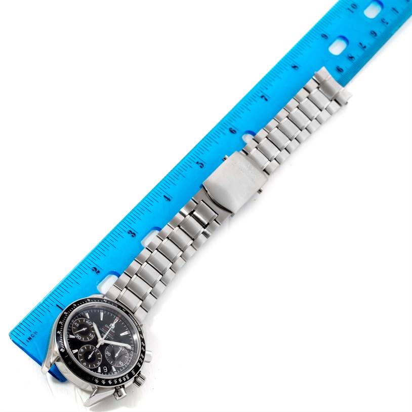 The Omega Speedmaster 323.30.40.40.01.001 Men
s Stainless Steel Black Dial 323.30.40.40.01.001 Men
s Stainless Steel Black Dial watch is shown lying flat, featuring its face, bezel, crown, and a stainless steel bracelet next to a blue ruler.