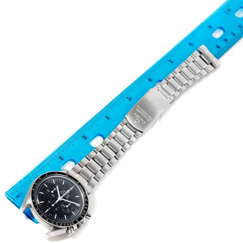 The Omega Speedmaster 3570.50.00 Men
s Stainless Steel Black Dial 3570.50.00 Men
s Stainless Steel Black Dial watch is shown flat with an emphasis on its metal bracelet and clasp, alongside a blue ruler for scale.