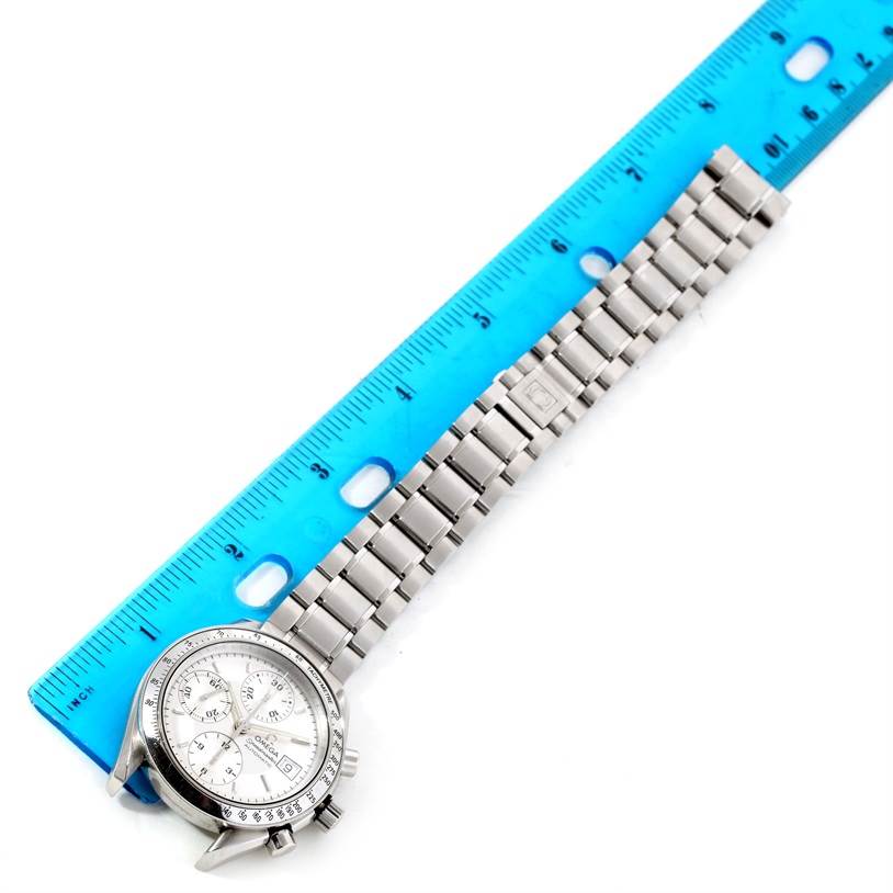 The image shows an Omega Speedmaster 3513.30.00 Men
s Stainless Steel Silver Dial 3513.30.00 Men
s Stainless Steel Silver Dial watch laid flat next to a blue ruler, displaying its face and metal bracelet.