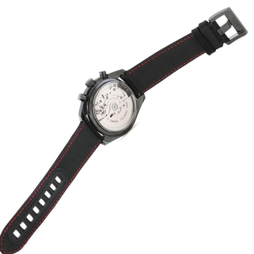 The image shows the back view of an Omega Speedmaster 311.92.44.51.01.003 Men
s Stainless Steel Black Dial 311.92.44.51.01.003 Men
s Stainless Steel Black Dial watch, revealing the movement and black strap with red stitching.