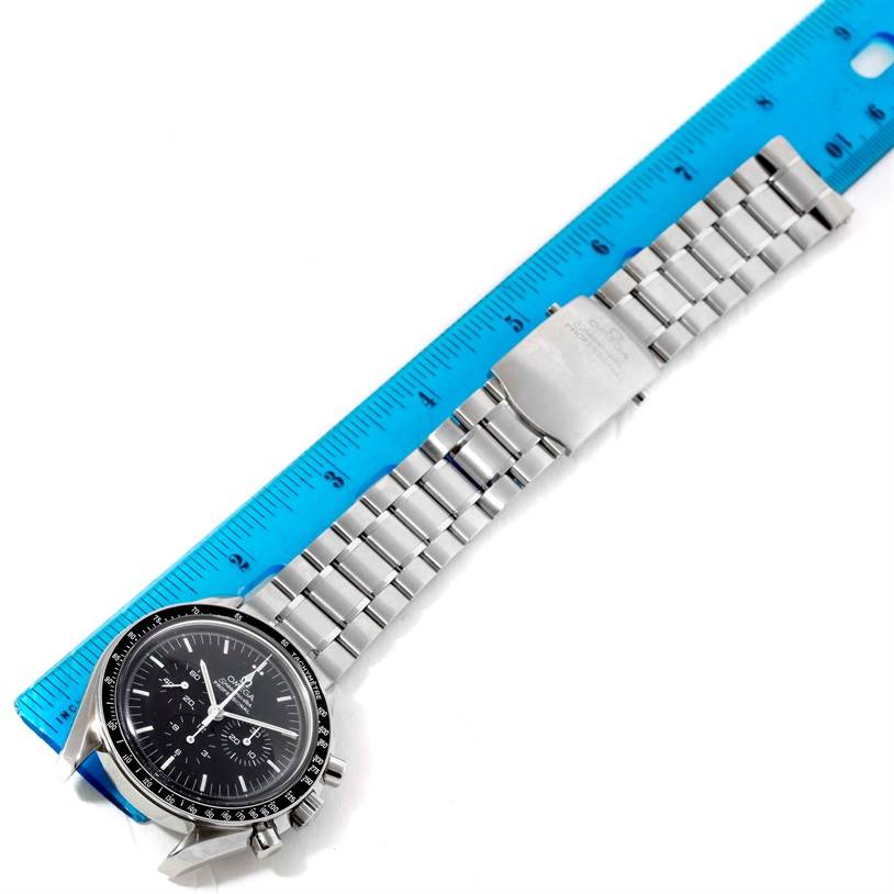 The Omega Speedmaster 3570.50.00 Men
s Stainless Steel Black Dial 3570.50.00 Men
s Stainless Steel Black Dial watch is shown at a slight angle with open clasp, placed alongside a blue ruler for scale.