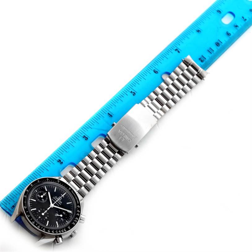The image shows an Omega Speedmaster 3539.50.00 Men
s Stainless Steel Black Dial 3539.50.00 Men
s Stainless Steel Black Dial watch and its metal bracelet laid next to a blue ruler for measurement.