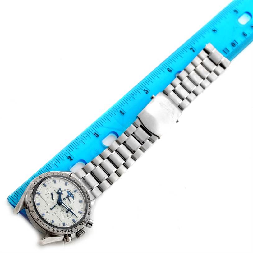 The Omega Speedmaster 3575.20.00 Men
s Stainless Steel White Dial 3575.20.00 Men
s Stainless Steel White Dial watch is shown from a top-down angle, featuring the watch face, bezel, and metal bracelet beside a blue ruler.