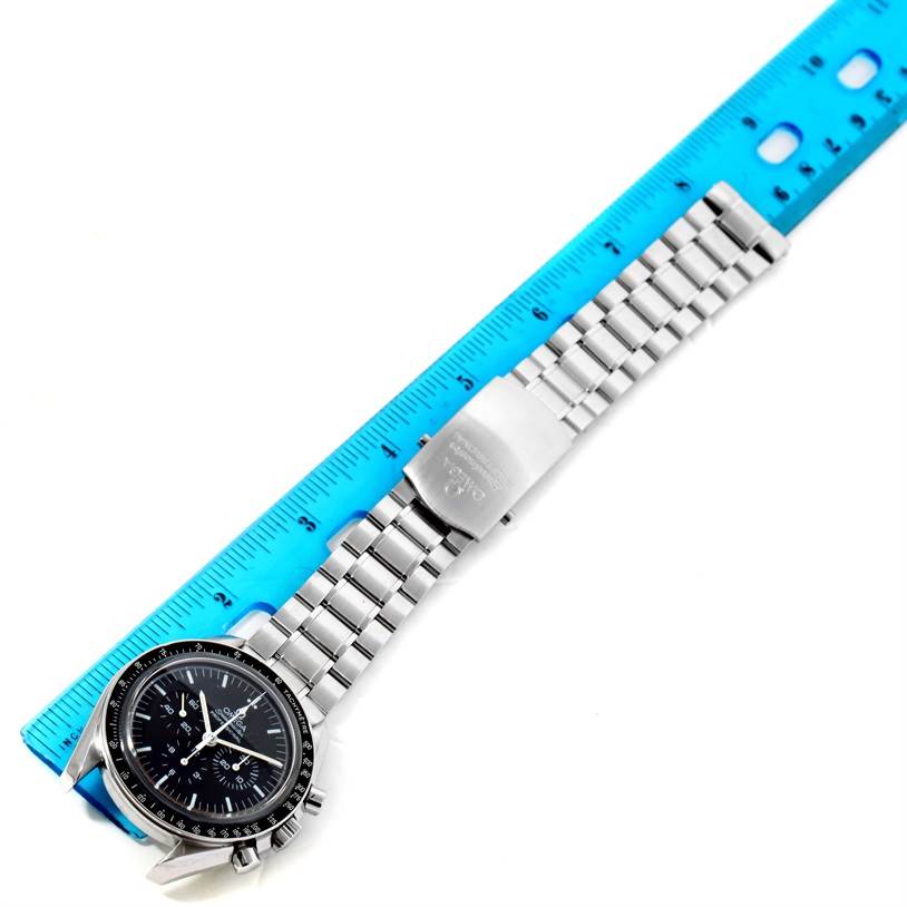 The Omega Speedmaster 3573.50.00 Men
s Stainless Steel Black Dial 3573.50.00 Men
s Stainless Steel Black Dial watch is shown from a top-down angle, with its stainless steel bracelet and clasp visible alongside a blue ruler.