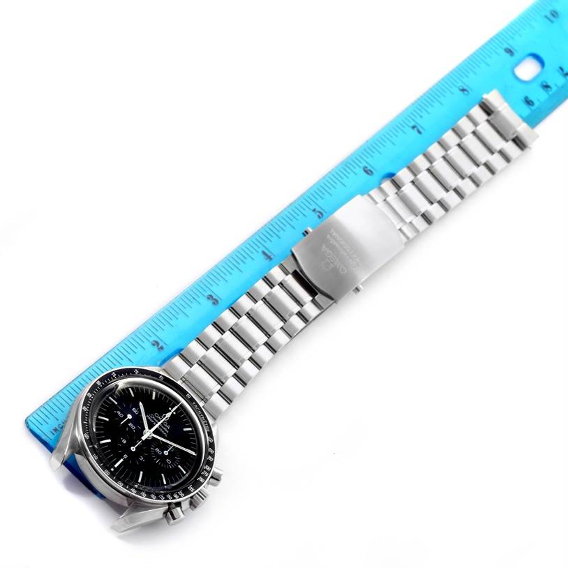 The Omega Speedmaster 3570.50.00 Men
s Stainless Steel Black Dial 3570.50.00 Men
s Stainless Steel Black Dial watch is shown from an overhead angle, displaying its face and stainless steel bracelet against a blue ruler.