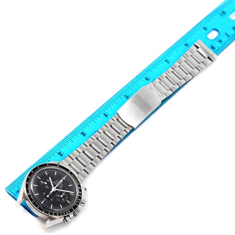 The Omega Speedmaster 3560.50.00 Men
s Stainless Steel Black Dial 3560.50.00 Men
s Stainless Steel Black Dial watch is shown from a top-down angle, including the face, bezel, and full metal bracelet next to a blue ruler.