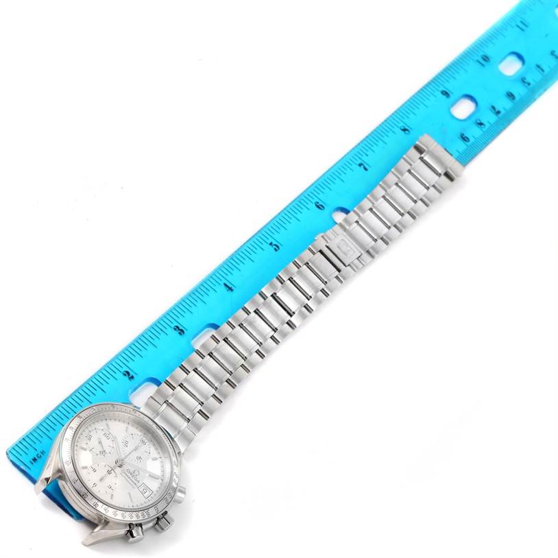 The photo shows an Omega Speedmaster 3513.30.00 Men
s Stainless Steel Silver Dial 3513.30.00 Men
s Stainless Steel Silver Dial watch laid flat, next to a blue ruler measuring its length.