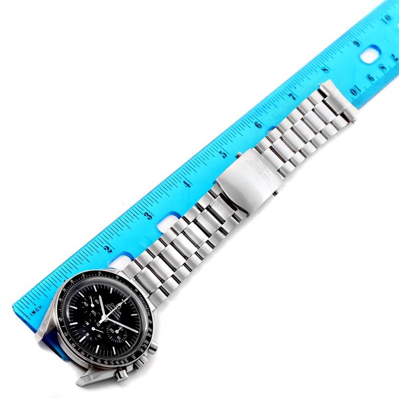 The image shows the Omega Speedmaster 3570.50.00 Men
s Stainless Steel Black Dial 3570.50.00 Men
s Stainless Steel Black Dial watch laid out flat with a blue ruler underneath it.