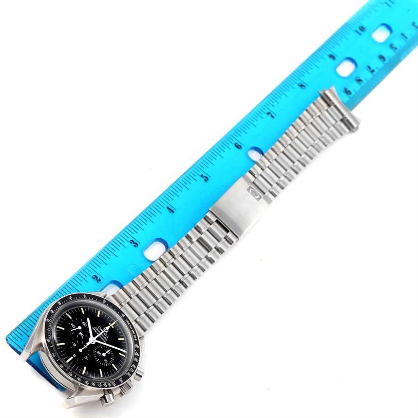 The Omega Speedmaster Men
s Stainless Steel Black Dial Men
s Stainless Steel Black Dial watch, shown from a top-down angle, is next to a blue ruler for scale; highlighting its face and linked bracelet.