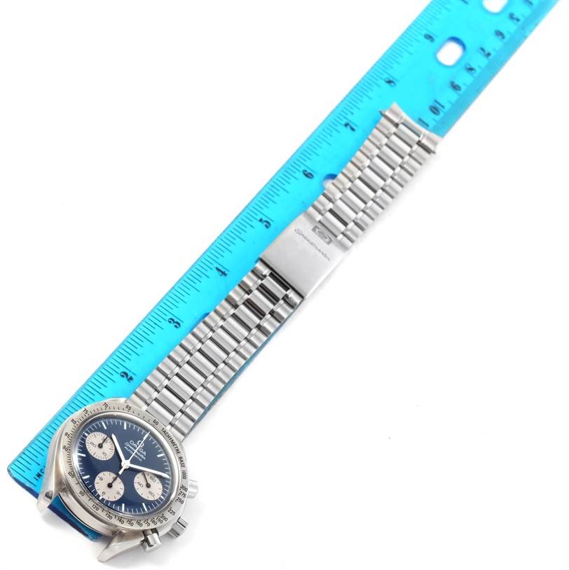 The Omega Speedmaster 3510.82.00 Men
s Stainless Steel Blue Dial 3510.82.00 Men
s Stainless Steel Blue Dial watch is shown diagonally, displaying the dial, bezel, crown, pushers, and stainless steel bracelet alongside a blue ruler.
