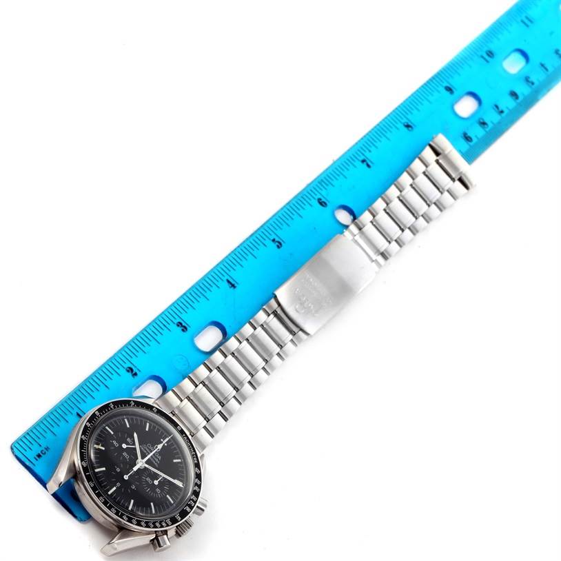 The image shows an Omega Speedmaster 3570.50.00 Men
s Stainless Steel Black Dial 3570.50.00 Men
s Stainless Steel Black Dial watch with its band laid next to a blue ruler for measurement.