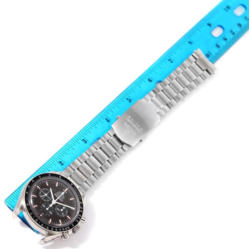 The Omega Speedmaster 3552.59.00 Men
s Stainless Steel Black Dial 3552.59.00 Men
s Stainless Steel Black Dial watch is shown from an overhead angle, displaying the dial, bracelet, and clasp next to a blue ruler.