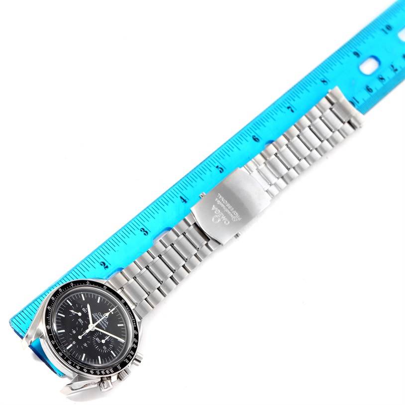 The image shows an Omega Speedmaster 3570.50.00 Men
s Stainless Steel Black Dial 3570.50.00 Men
s Stainless Steel Black Dial watch laid flat, with a blue ruler measuring its stainless steel bracelet.