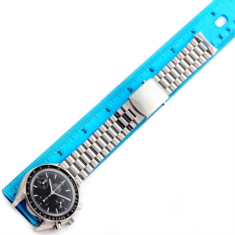 The image shows an Omega Speedmaster 3539.50.00 Men
s Stainless Steel Black Dial 3539.50.00 Men
s Stainless Steel Black Dial watch laid flat next to a blue ruler, highlighting its metal bracelet and clasp.