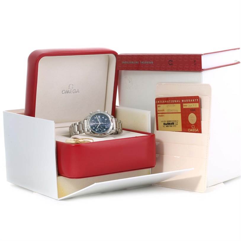 The image shows an Omega Speedmaster 3513.82.00 Men
s Stainless Steel Blue Dial 3513.82.00 Men
s Stainless Steel Blue Dial watch in its open red box, alongside warranty cards and a booklet.