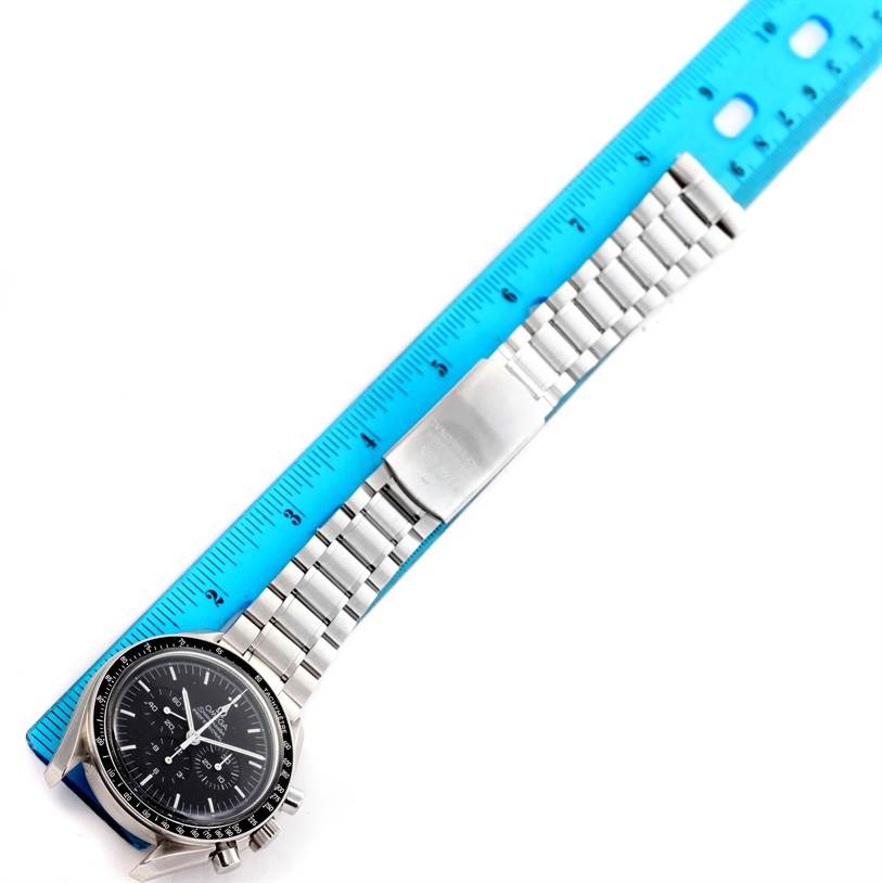 The Omega Speedmaster 3560.50.00 Men
s Stainless Steel Black Dial 3560.50.00 Men
s Stainless Steel Black Dial watch is shown from an overhead angle, displaying the face, bracelet, and clasp near a blue ruler.