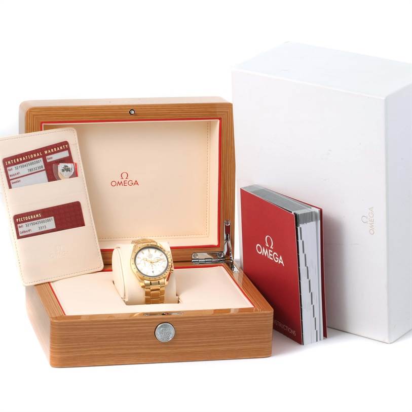 The Omega Speedmaster 321.50.42.50.02.001 Men's Yellow Gold Silver Dial 321.50.42.50.02.001 Men's Yellow Gold Silver Dial watch is shown in an open box with its accessories, including warranty cards and a manual.